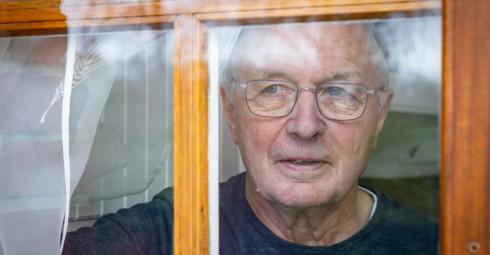 Une personne âgée regarde par la fenêtre